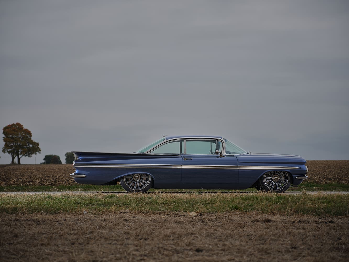 1959 Chevrolet Impala custom hardtop side view lowered suspension deep dish wheels farmland backdrop