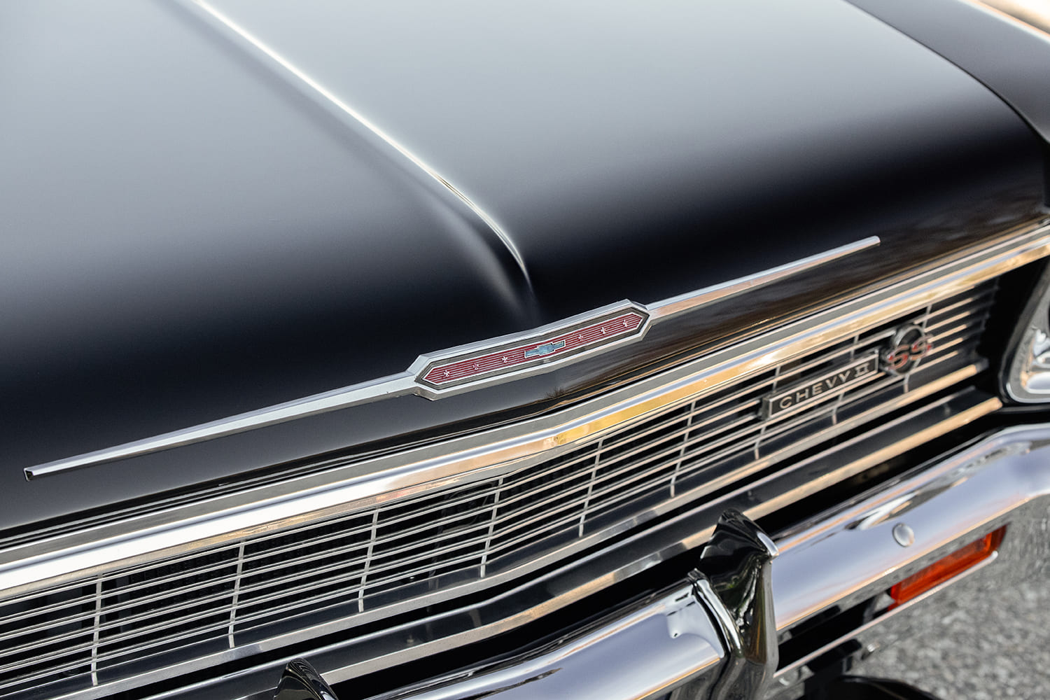 Front hood lip and chrome trim detail showing the vintage Chevy II emblem and SS badge mounted in the horizontal bar grille.