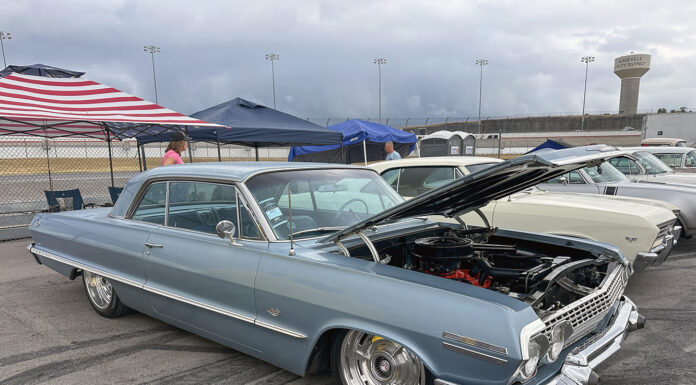 The 4th Annual Triple Crown of Rodding Car Show Low front three-quarter view of a slammed slate-blue 1963 Chevrolet Impala hardtop with an open hood, chrome grille, and large polished wheels.