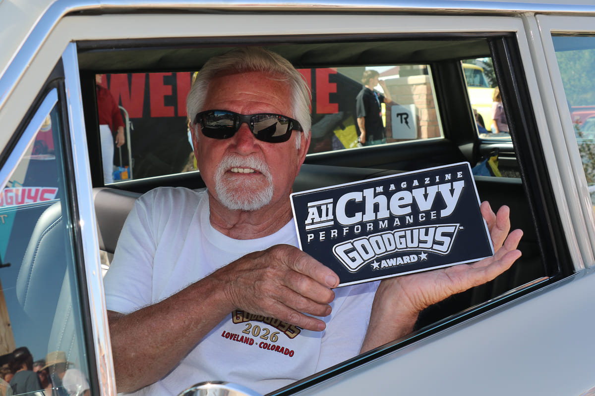Driver smiling from inside his classic Chevy wagon while displaying his All Chevy Performance Magazine Goodguys Award plaque.