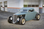 Low-angle front view of a slate blue-teal chopped 1933 Ford 3-Window Coupe highlighting the exposed front suspension and open engine bay.