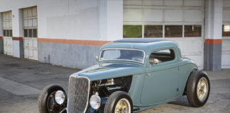 Low-angle front view of a slate blue-teal chopped 1933 Ford 3-Window Coupe highlighting the exposed front suspension and open engine bay.