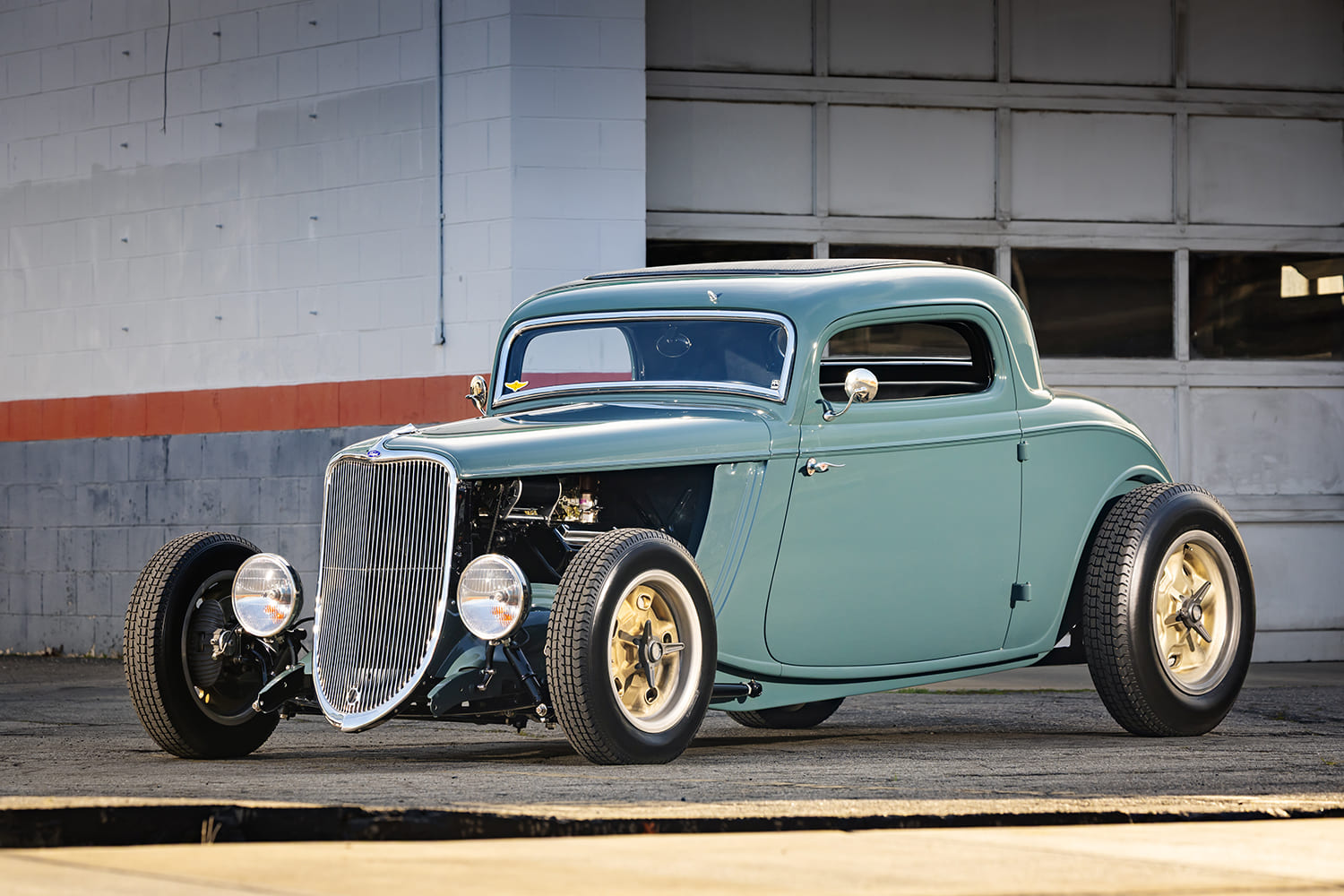 Ground-level front three-quarter view of a custom 1933 Ford 3-Window Coupe street rod with vintage round headlights and deep-dish gold wheels.