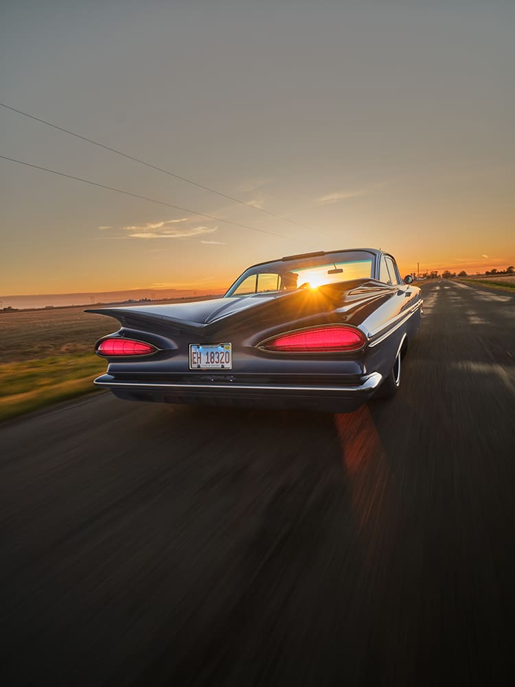 1959 Chevrolet Impala rear view rolling sunset photo blue custom coupe tailfins illuminated taillights