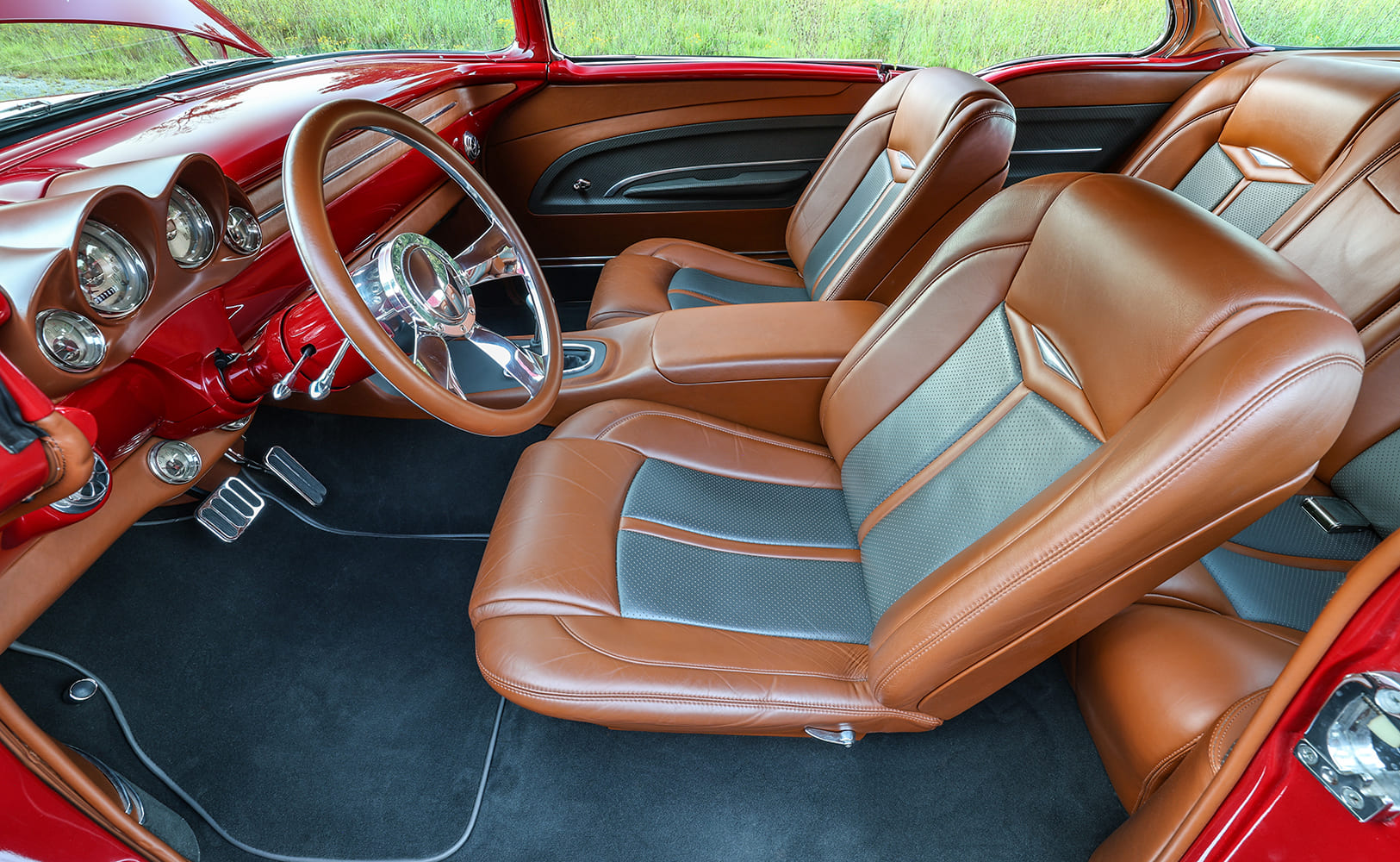 Interior passenger view of a custom 1955 Bel Air featuring saddle brown and gray leather bucket seats with a matching steering wheel.