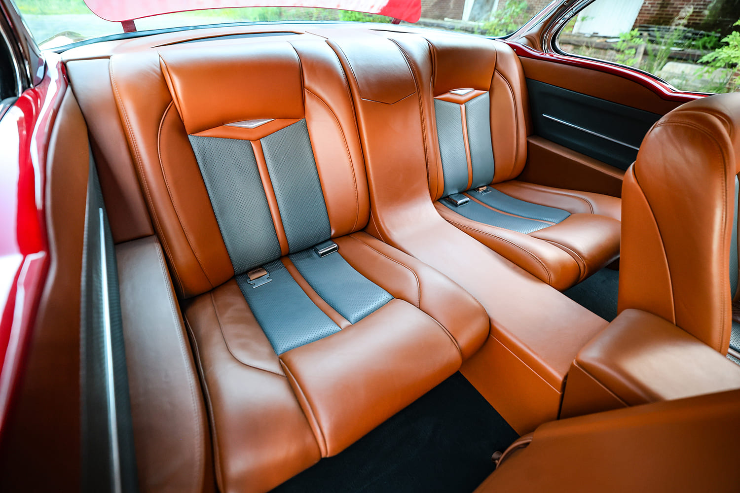 Close-up of the rear bucket-style bench seat upholstered in two-tone brown and slate leather inside a custom 1955 Chevy Bel Air.