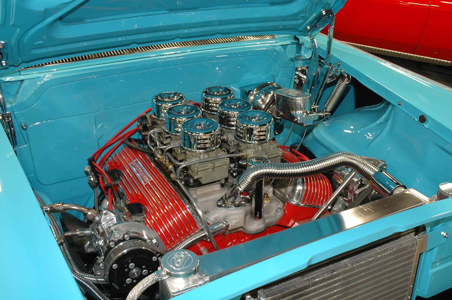 409 with red finned valve covers and six carburetors in a blue tri-five Chevy