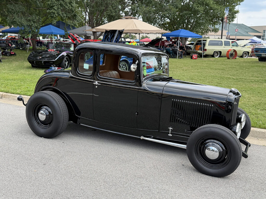 Front three-quarter view of a traditional black 1932 Ford five-window coupe highboy street rod without fenders on black steel wheels and tall pie-crust tires.