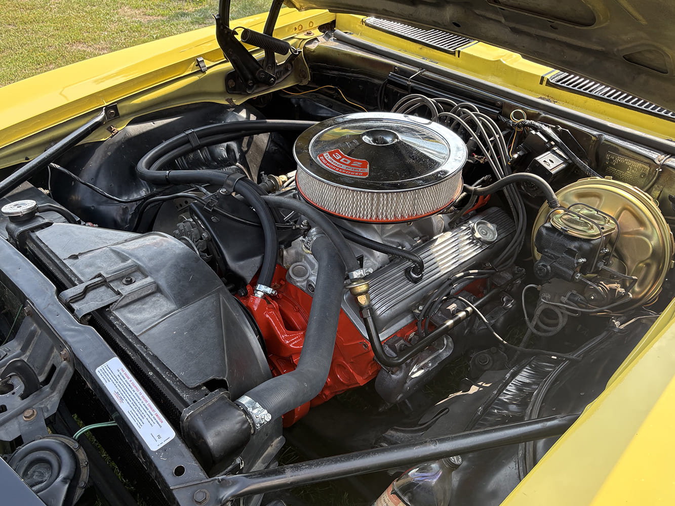 302 V8 engine compartment in a 1969 Camaro Z28 showing chrome air cleaner, brake booster, and alternator.