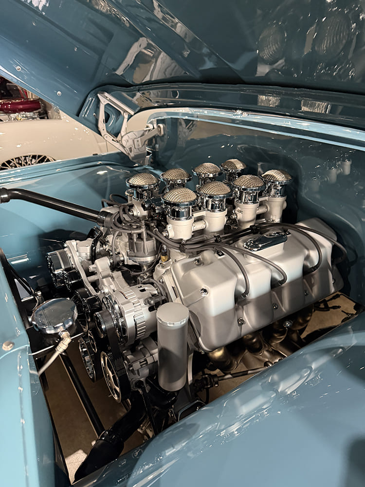 Detailed close-up of a high-performance engine bay featuring an eight-stack induction system with mesh bell tops in a custom pastel blue engine bay.