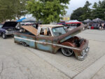 2026 Goodguys Columbus Nationals Trucks Front three-quarter angle of a slammed weathered Chevy C10 pickup with an open hood, raised wood bed floor, and chrome-rimmed wheels outdoors.