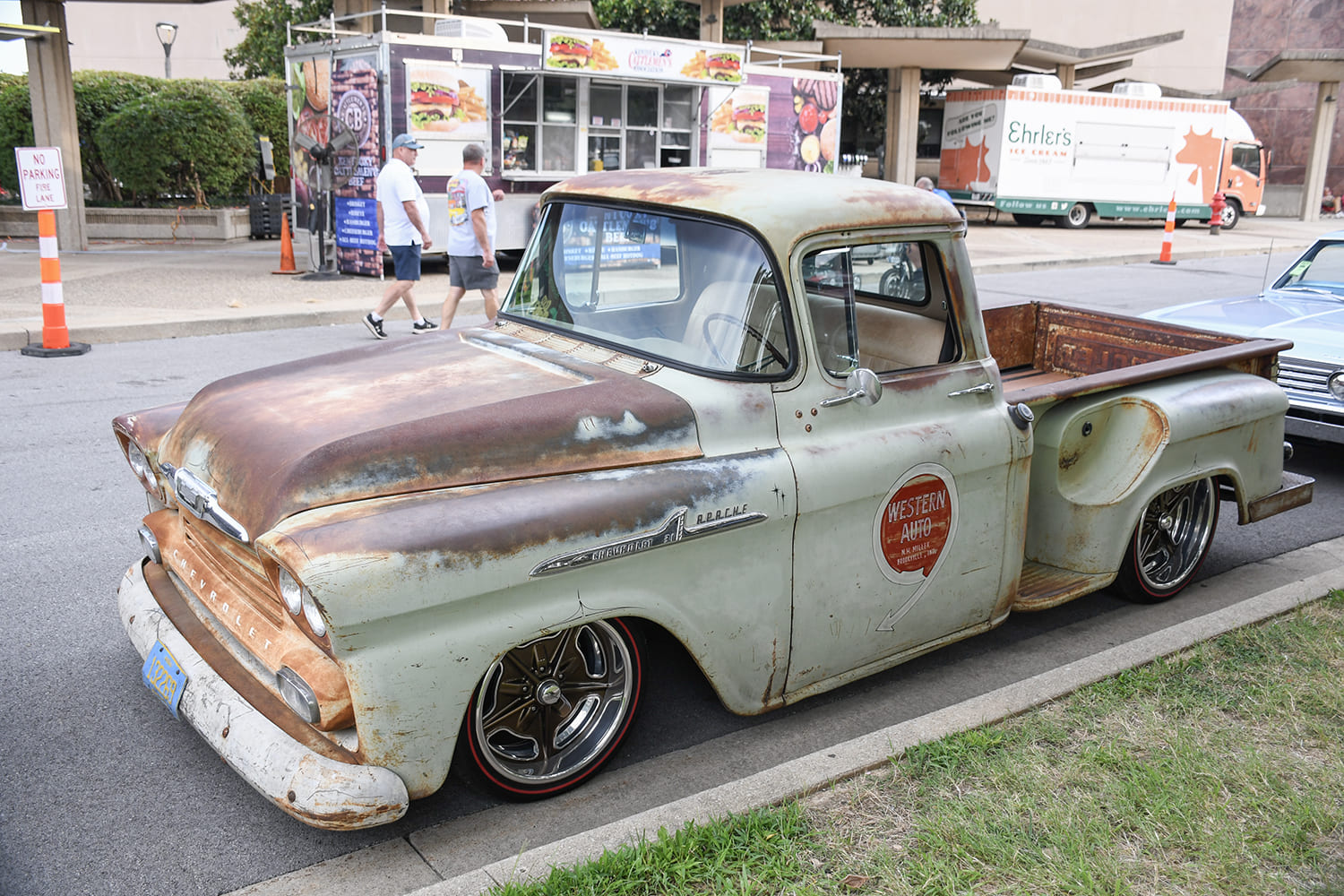 Low-angle side three-quarter view of a weathered patina light green Chevrolet Apache stepside pickup with Western Auto door lettering and deep-dish wheels.