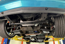 Underside view of an OBS Chevy truck on a lift showing an installed Flaming River rack-and-pinion steering conversion kit with tubular control arms and aftermarket suspension.
