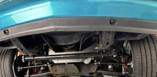 Underside view of an OBS Chevy truck on a lift showing an installed Flaming River rack-and-pinion steering conversion kit with tubular control arms and aftermarket suspension.
