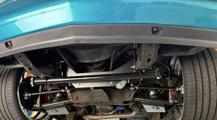OBS Chevy Rack and Pinion Conversion | Flaming River Underside view of an OBS Chevy truck on a lift showing an installed Flaming River rack-and-pinion steering conversion kit with tubular control arms and aftermarket suspension.