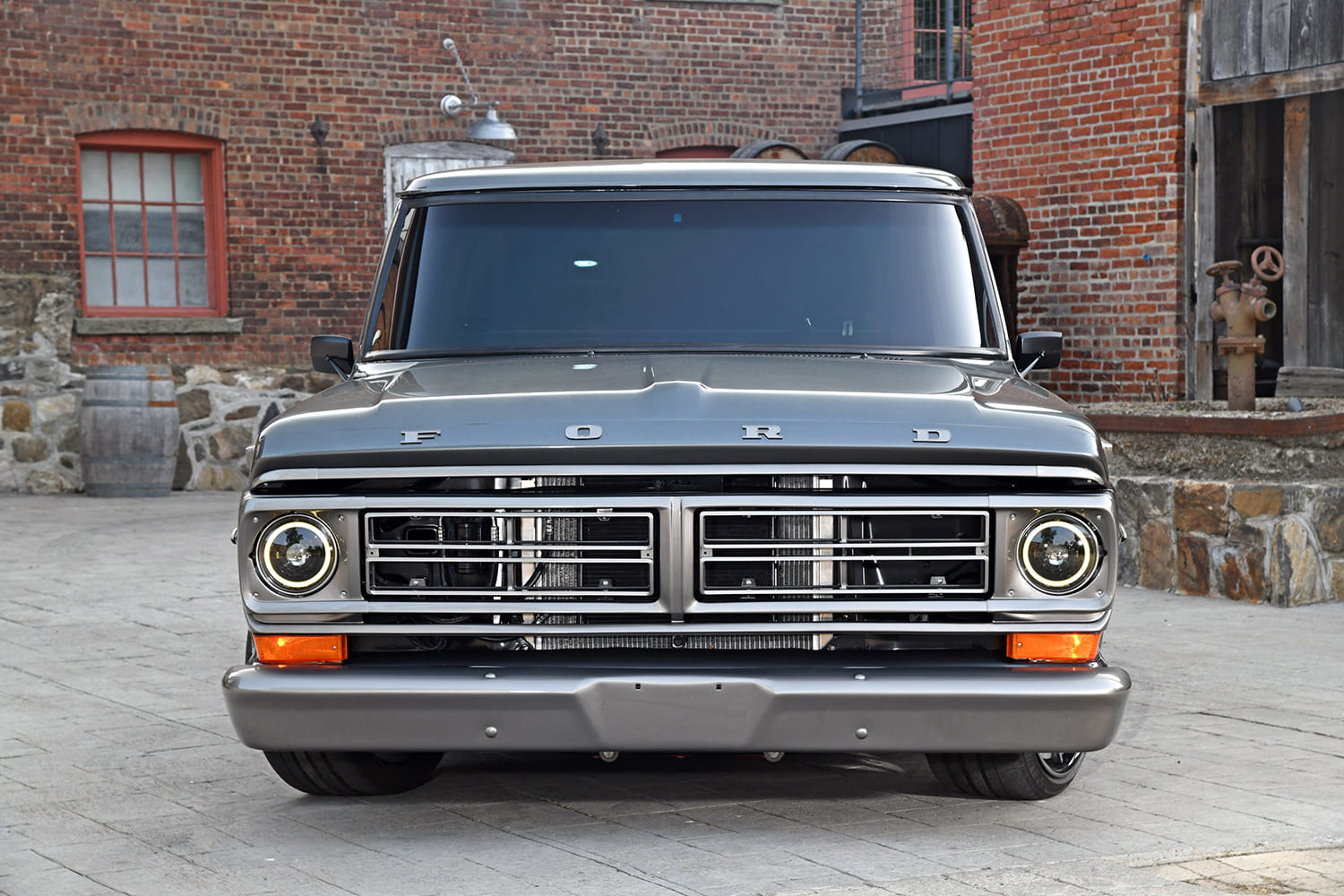 Direct head-on view of the gray painted bumper, custom split grille, and modern halo projector headlights on a 1972 Ford Bumpside truck.