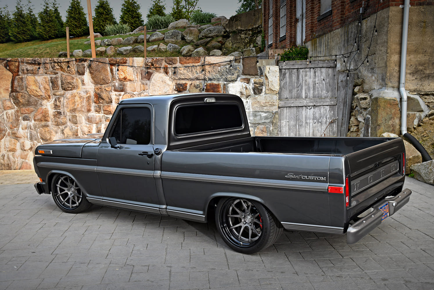 High rear three-quarter shot of a 1972 Ford F-100 Sport Custom pickup truck highlighting the clean bed, side trim, and modern deep-dish wheels.