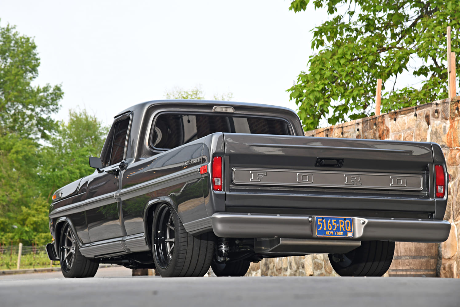 Low-angle rear view of a custom 1972 Ford F-100 showing embossed tailgate, smooth bumper, and massive wide rear performance tires.