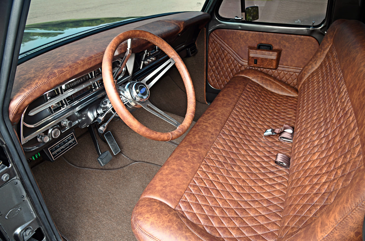 Wide interior cab view of a 1972 Ford F-100 truck featuring diamond-stitched brown leather bench upholstery, matching leather-wrapped dash, and custom steering wheel.