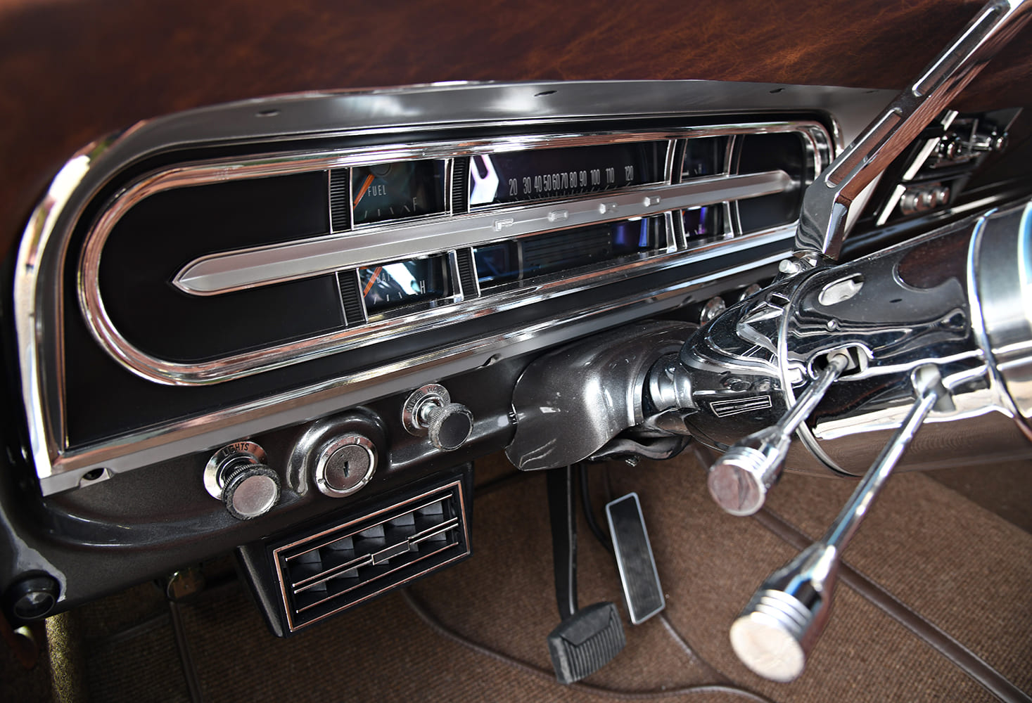 Close-up of the chrome instrument cluster bezel with backlit digital gauges, polished tilt steering column, and climate control vents on a 1972 Ford F-100 dash.