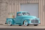 Chris Koehler’s 1953 Five Window Chevy Truck Front three-quarter view of a custom lowered 1953 Chevrolet 3100 pickup truck painted seafoam turquoise with whitewall tires and chrome grille parked outside a garage.