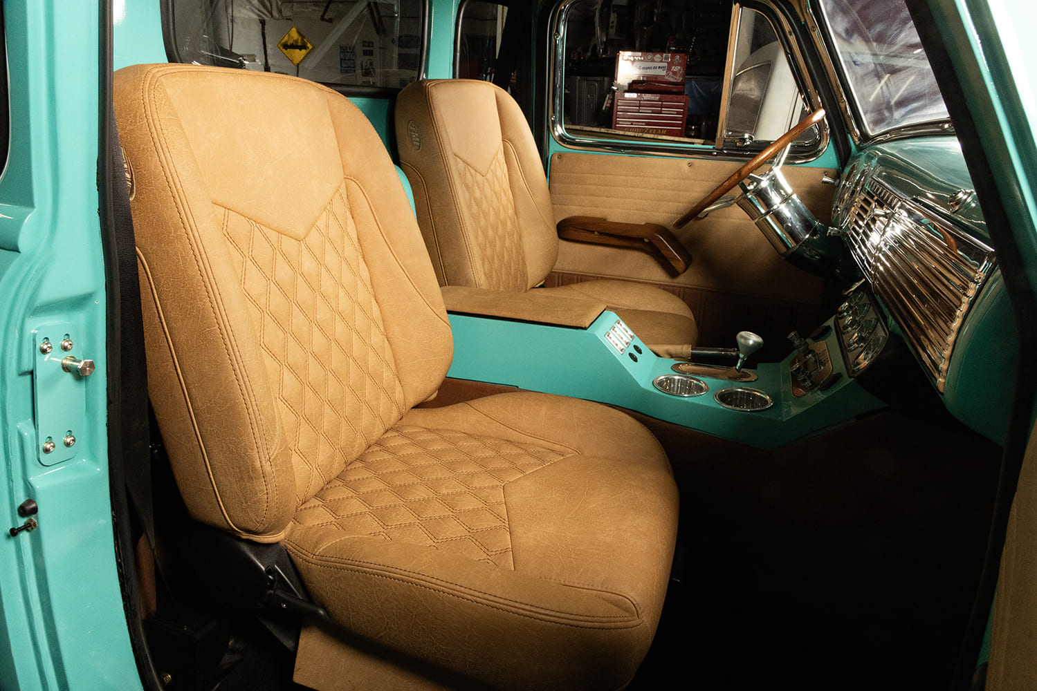 Interior cabin view of a custom 1953 Chevrolet truck highlighting bolstered tan upholstery bucket seats with diamond stitching and full center console.