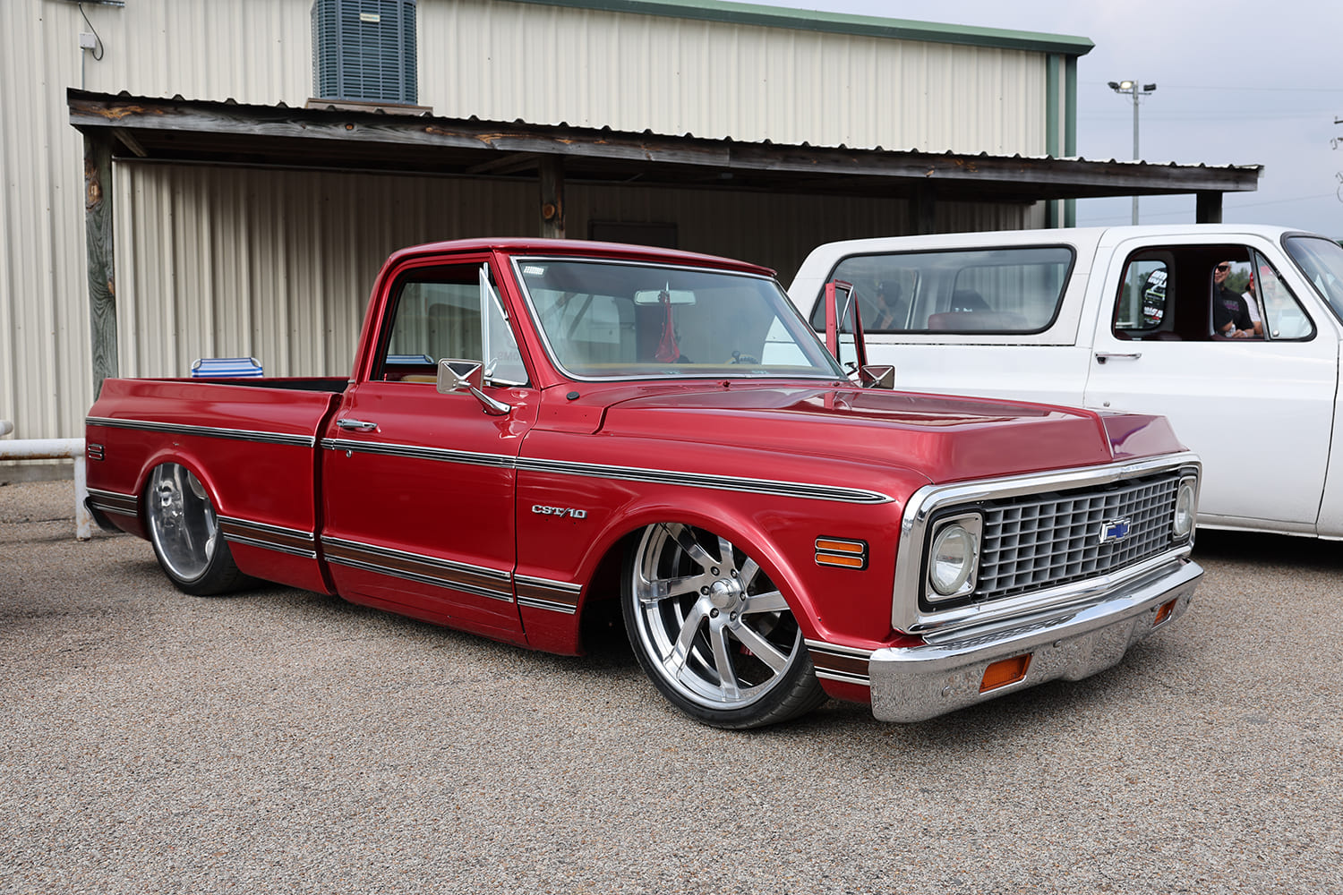 Low-angle front three-quarter view of a lowered metallic red 1971-1972 Chevrolet C10 CST pickup on polished directional wheels.