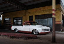 Low-angle front three-quarter perspective of a custom 1968 Chevy C10 pickup laid out on polished wheels in front of a weathered yellow brick building.