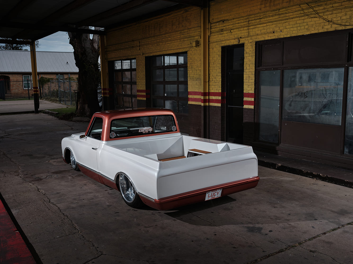 High rear three-quarter perspective of a slammed 1968 Chevy C10 pickup displaying smooth bed sides, copper roll pan bumper, and custom Texas license plate.