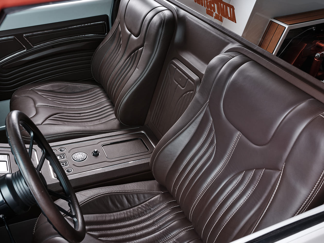 Angled view of the truck interior highlighting the custom dark brown leather high-back bucket seats with fluted stitching and custom center console