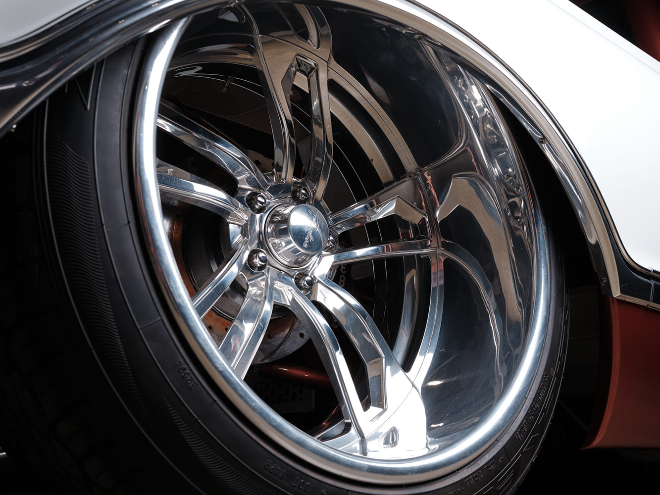Extreme low-angle view of the rear wheel tucked tightly under the rear fender showing deep-dish polished billet wheels and Wilwood disc brakes.