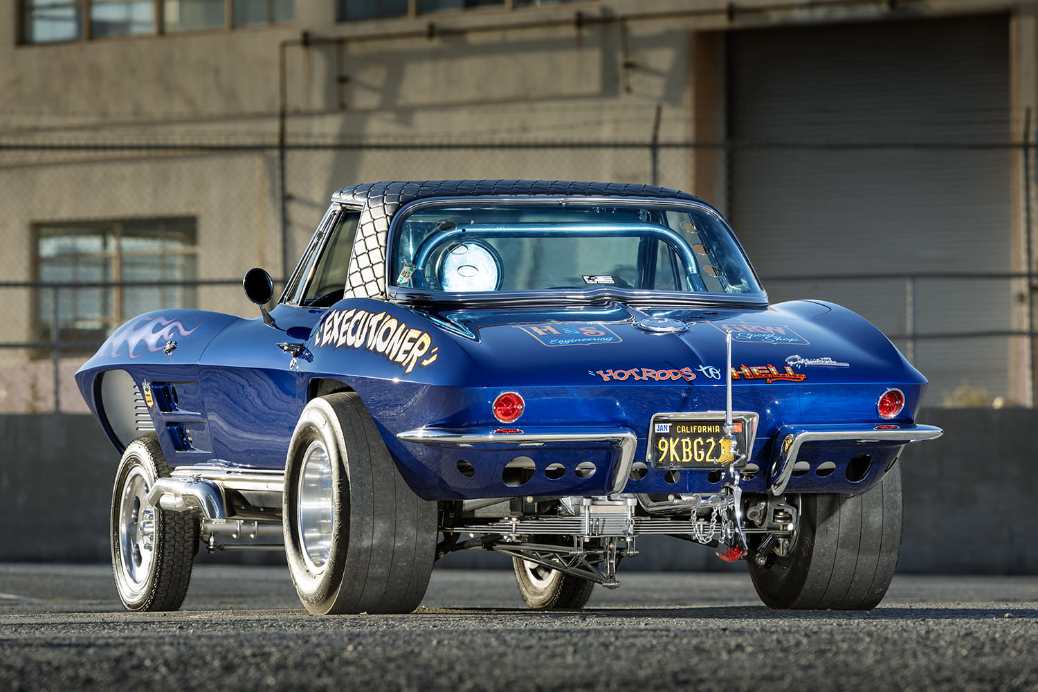 Rear view of a 1964 Corvette gasser displaying massive drag slicks, suspension linkage, and drilled rear valance panel.