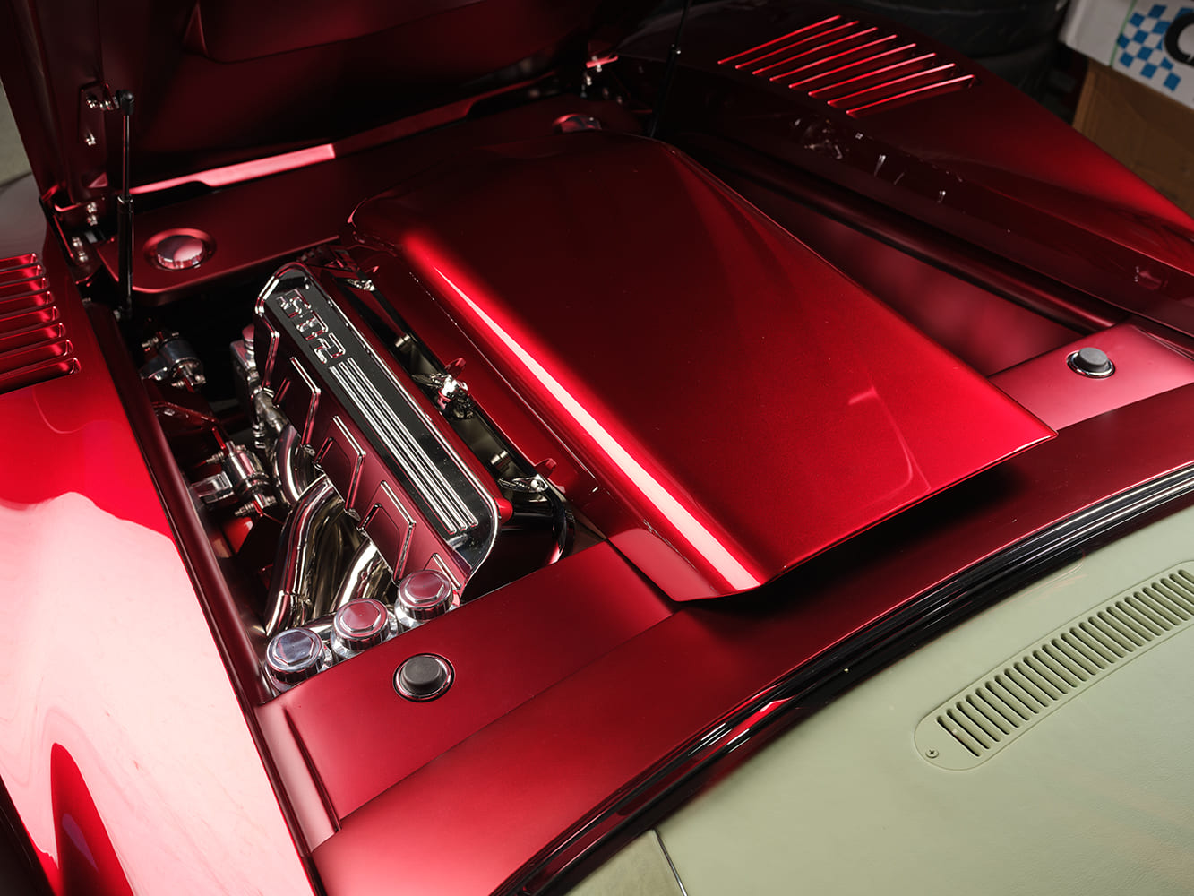 Driver-side underhood view of the 1972 Corvette showcasing a gloss red fabricated engine shroud and polished 582 big-block Chevrolet valve cover.