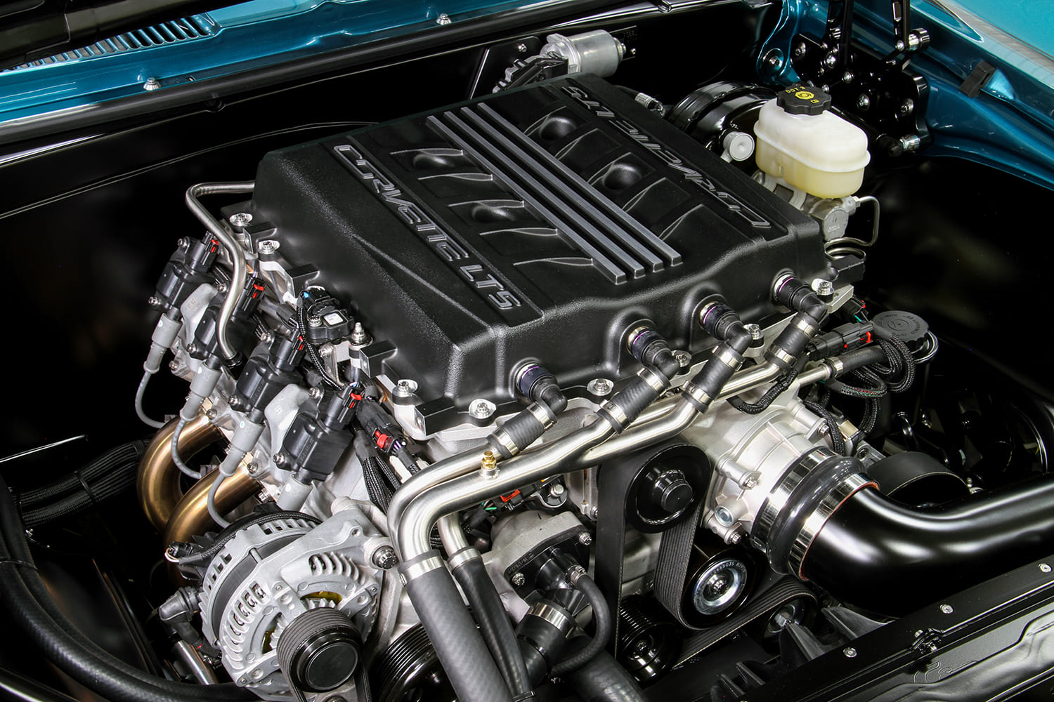 Clean engine bay of a 1967 Camaro fitted with a supercharged GM LT5 crate engine, serpentine drive, and stainless plumbing