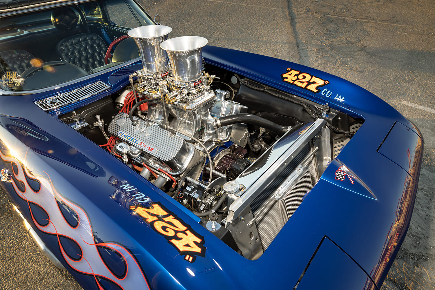 Overhead engine bay view of a 427-cubic-inch V8 equipped with dual carburetors, tall velocity stacks, and Nagel Racing valve covers.