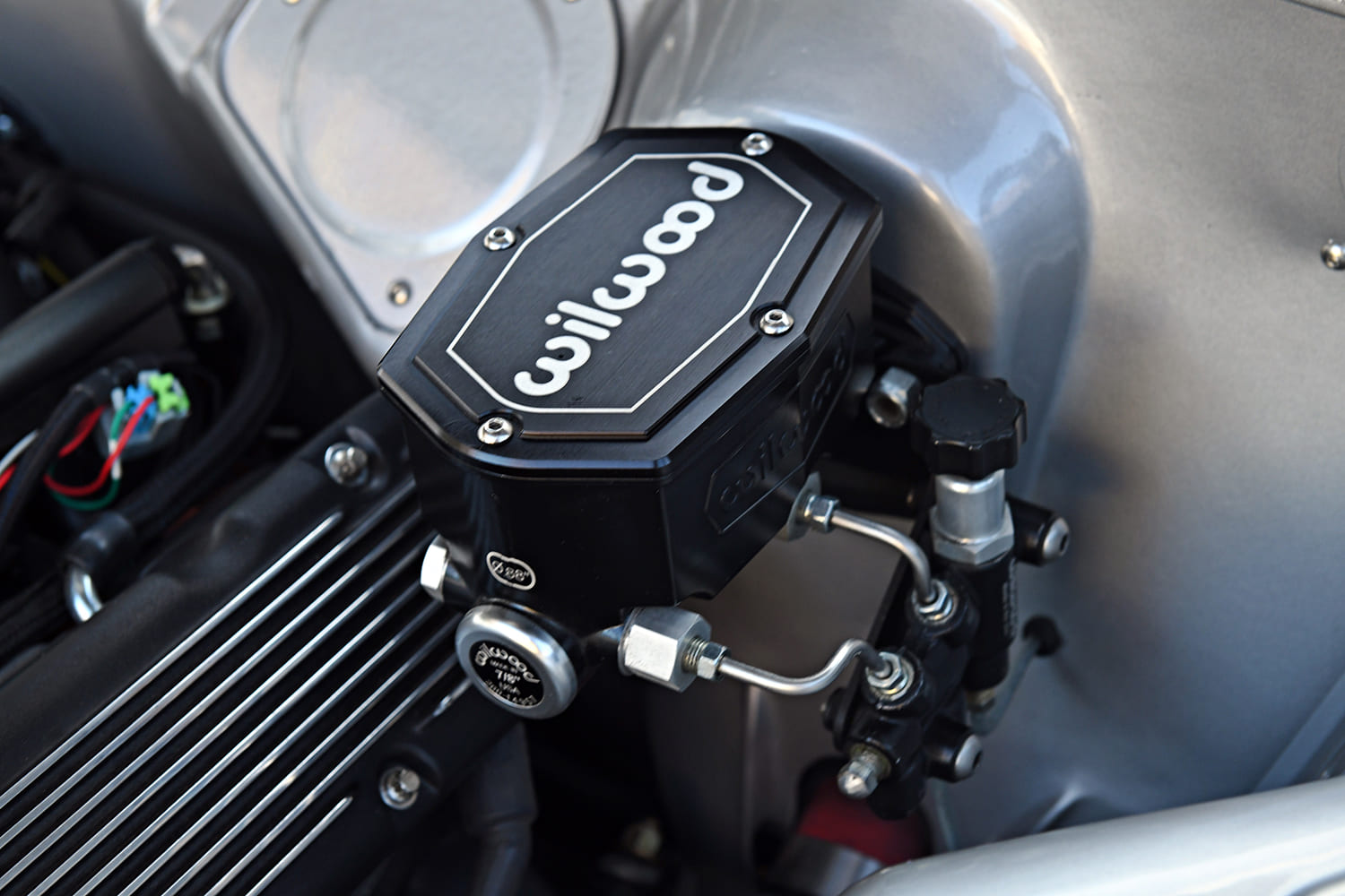 Detailed close-up of a black anodized Wilwood tandem master cylinder and brake proportioning valve with hardlines mounted to the smoothed firewall.