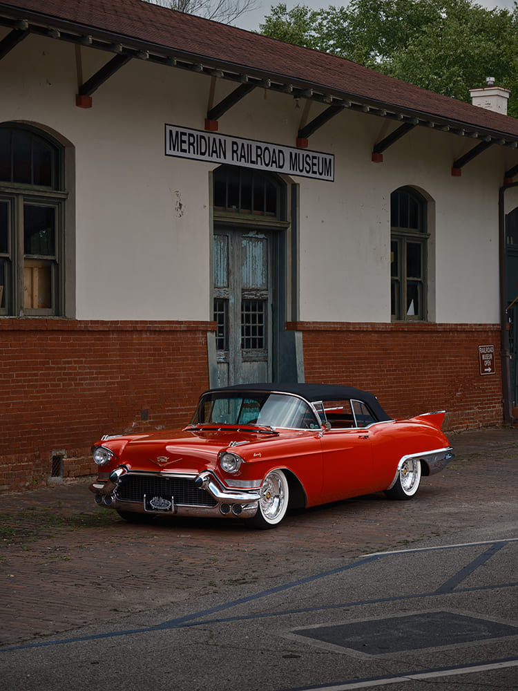 Front three-quarter vertical view of Doyle and Karen Thomas's Victory Red 1957 Cadillac Eldorado Biarritz convertible parked on brick pavers outside the Meridian Railroad Museum.