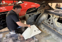 Installer test-fitting a precut Flatline Barriers insulation sheet over the rear floor pan in a stripped 1969 Chevelle interior.