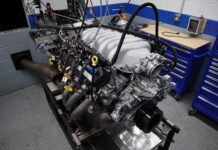 Front three-quarter angle of a Ford 7.3L Godzilla V8 test engine equipped with a cast aluminum Holley intake manifold and dyno exhaust headers on the test stand.