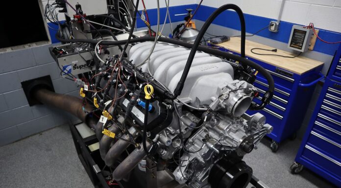 Front three-quarter angle of a Ford 7.3L Godzilla V8 test engine equipped with a cast aluminum Holley intake manifold and dyno exhaust headers on the test stand.