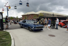 Dark blue 1967 Ford Mustang fastback with an exposed blower driving through the event gates under a ski lift at the Goodguys Columbus Nationals.
