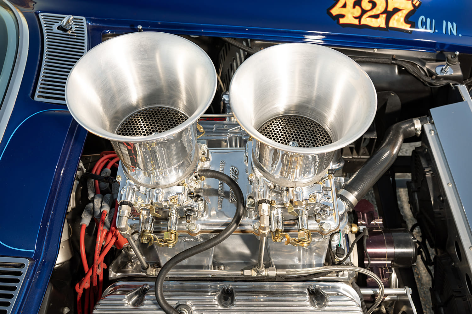 Close-up overhead shot of dual four-barrel carburetors with large polished velocity stacks on an Edelbrock tunnel ram intake manifold.