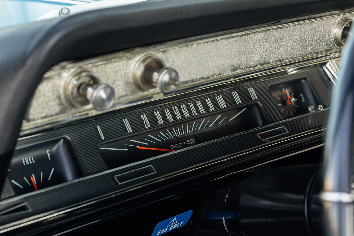 Close-up of the textured dash trim, horizontal 120-mph speedometer sweep, fuel level gauge, and analog clock in the 1966 Chevelle.