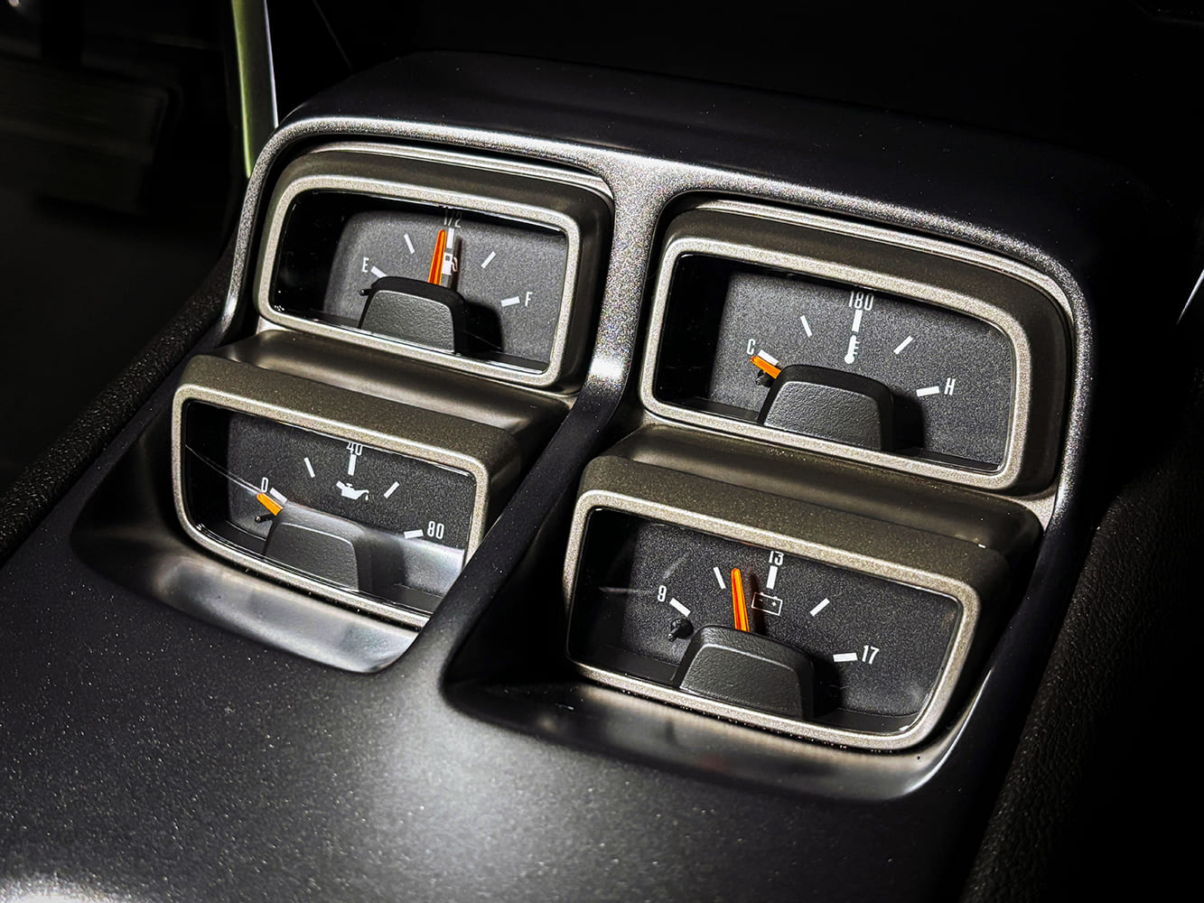 Close-up of four-pack console auxiliary gauges showing fuel level, coolant temperature, oil pressure, and battery voltage.