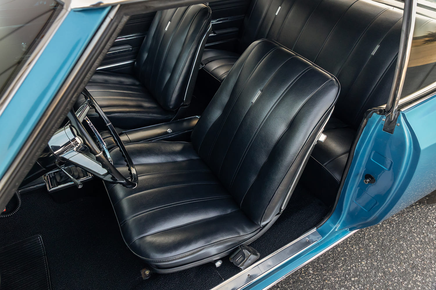 High interior perspective looking down at the black pleated vinyl bucket seats, factory center console, and rear seat in the Chevelle hardtop.