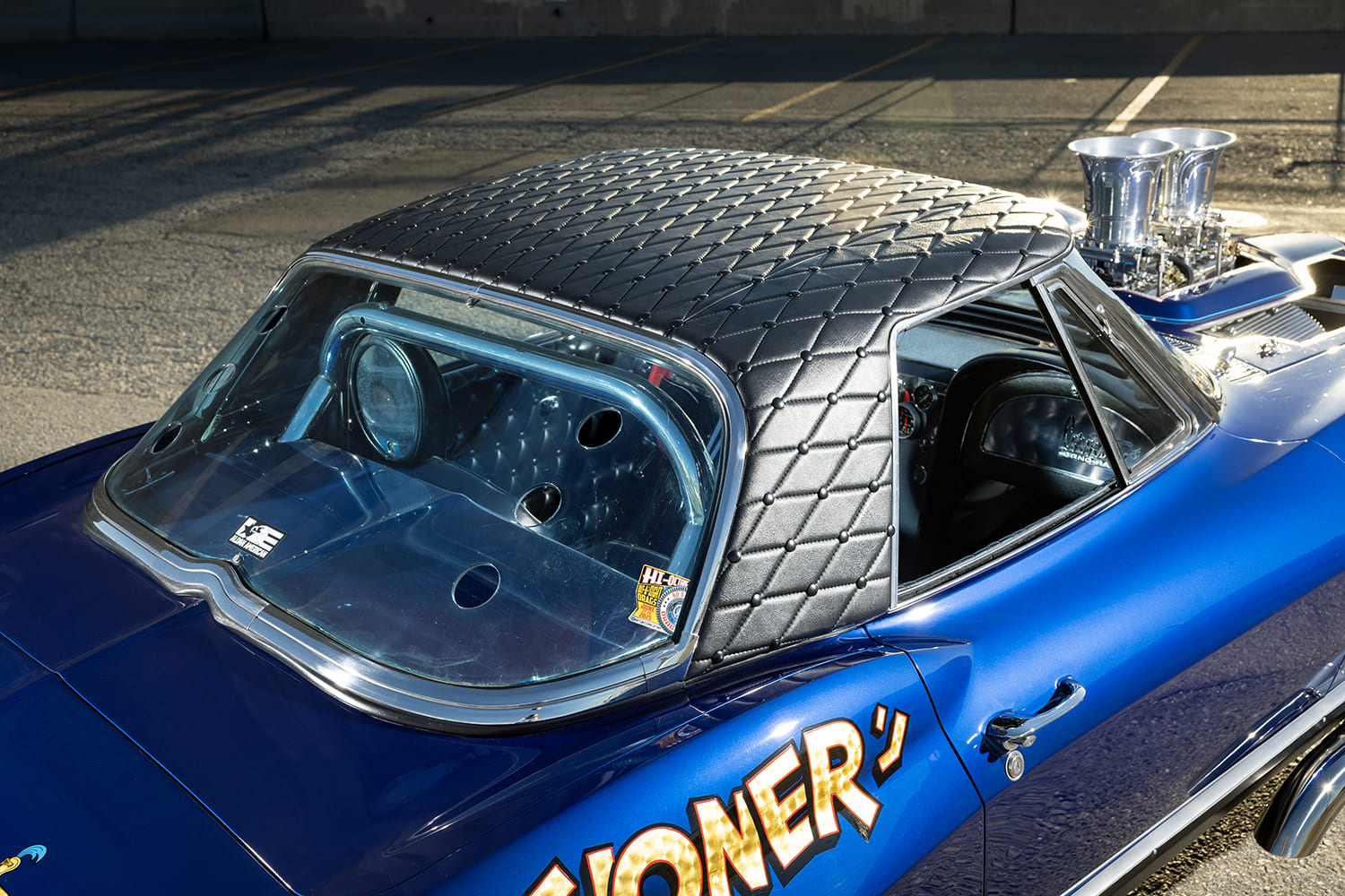 High-angle rear quarter view showing the black diamond-stitched padded vinyl hardtop and roll bar through the rear window.