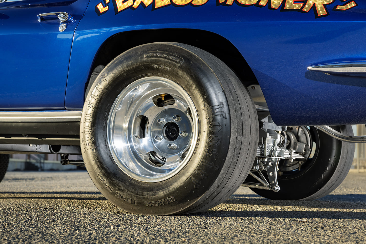 Low-angle side view of a wide Hoosier Quick Time Pro drag slick mounted on a deep-dish polished slotted wheel.