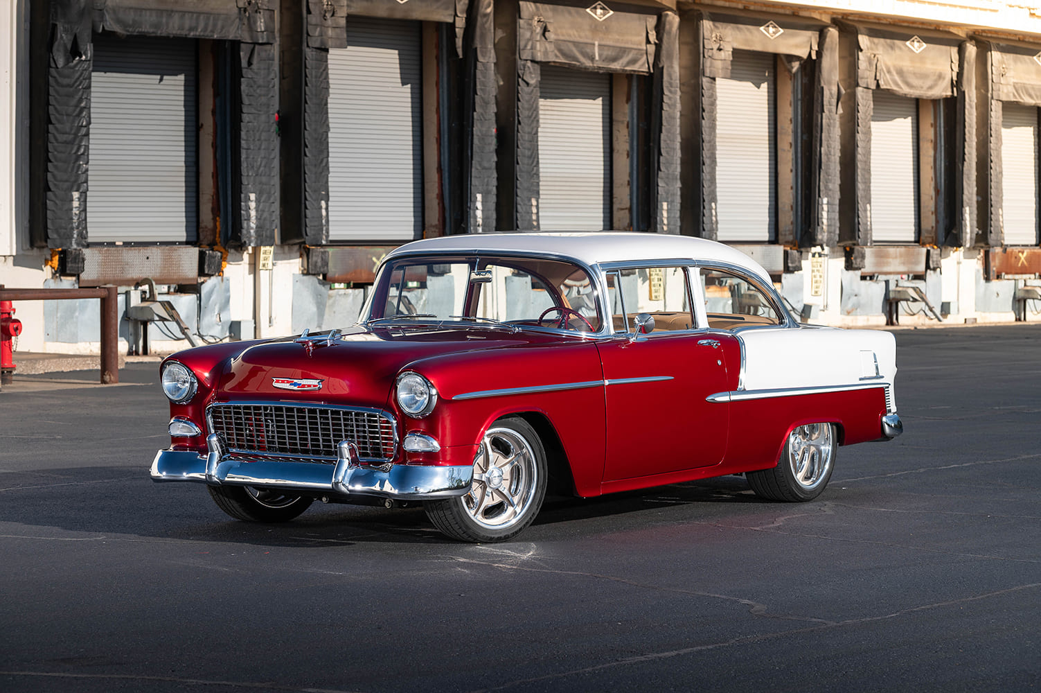 Low-angle front three-quarter view showing the chrome egg-crate grille, front bumper, and polished five-spoke wheels of a 1955 Chevy Bel Air.