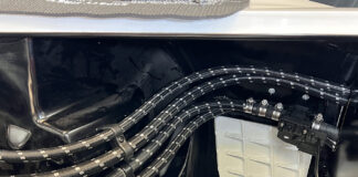 Clean routing of four black braided Pure Stealth hoses secured with billet chassis clamps along the gloss black inner fender and firewall.