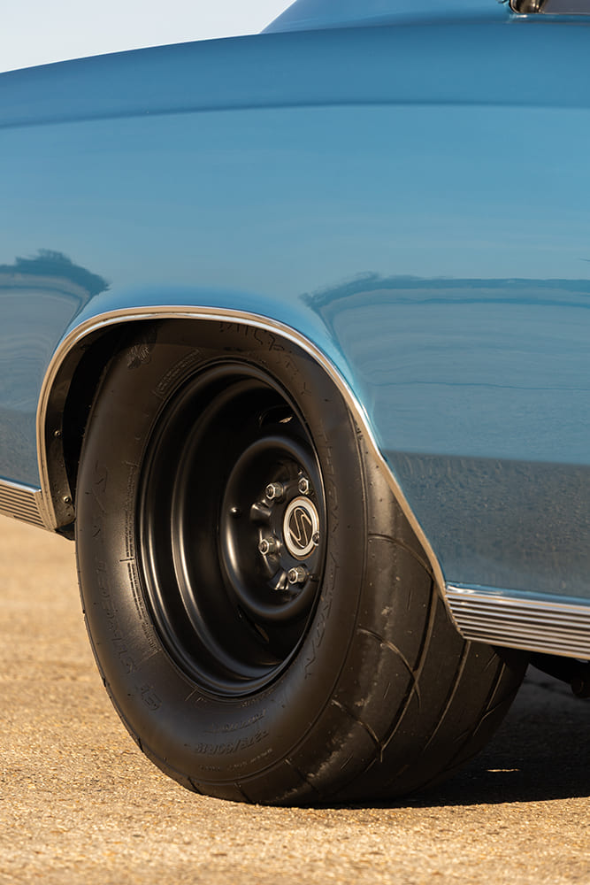 Detailed side shot of a wide Mickey Thompson ET Street drag radial tire mounted on a satin black steel-style wheel tucked neatly inside the rear fender.